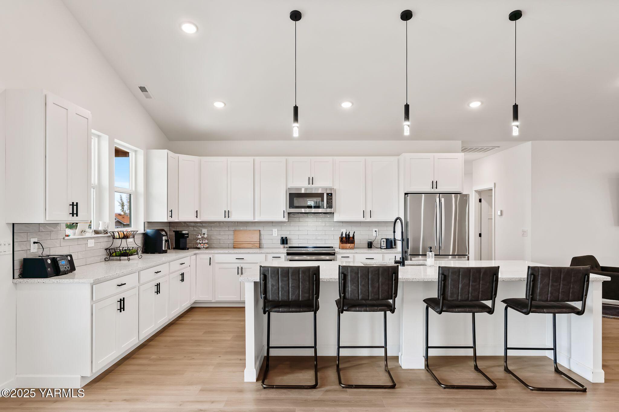 12907 Douglas Road Yakima, WA 98908 - Photo 9 of 44 a kitchen with stainless steel appliances kitchen island granite countertop a dining table chairs and white cabinets