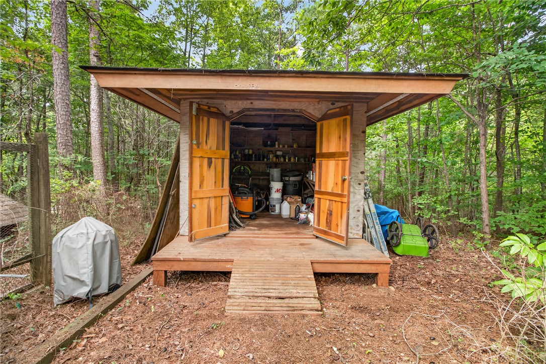 130 Maggie Rufus Lane Westminster, SC 29693 - Photo 37 of 50 A well-crafted wooden shed offers practical storage amidst a serene, wooded backdrop.