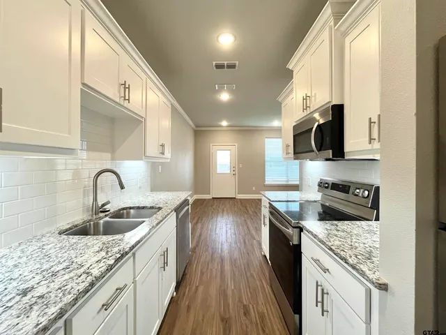 a kitchen with granite countertop a sink a counter space appliances and cabinets