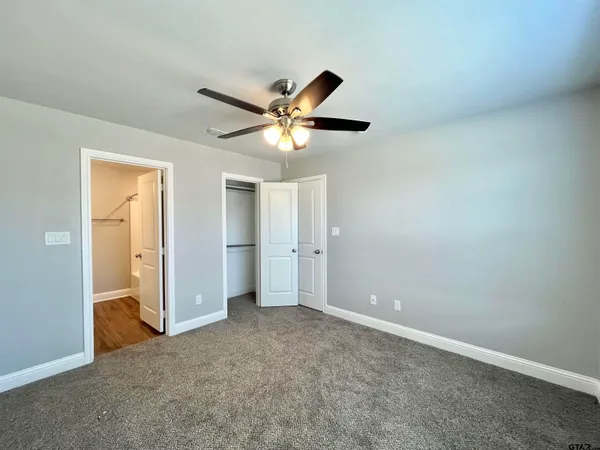 an empty room with closet and a chandelier fan