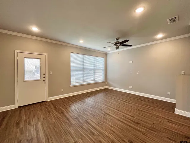 a view of an empty room with a window and wooden floor
