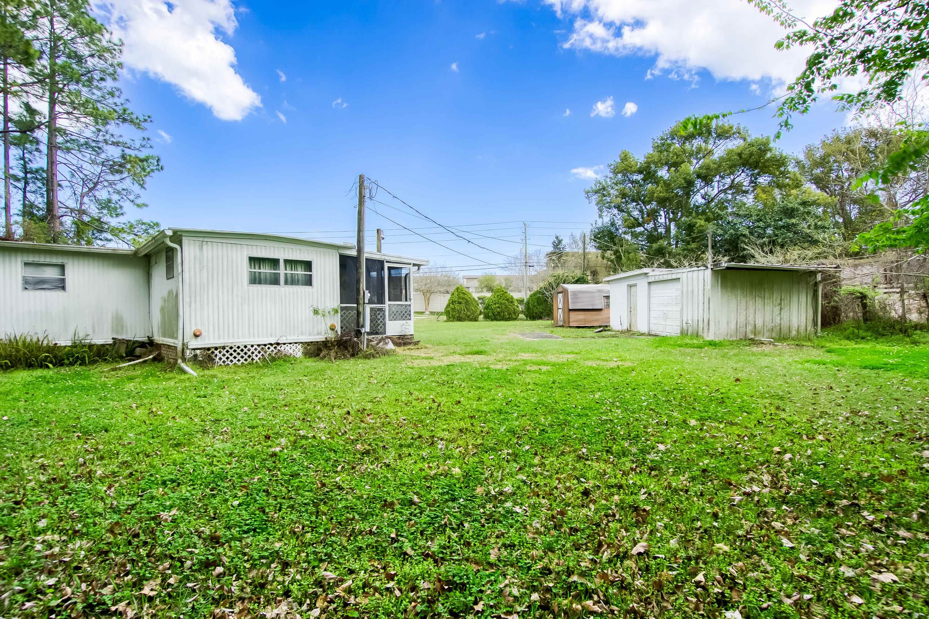 2785 Stratton Boulevard St. Augustine, FL 32084 - Photo 17 of 25 View of grassy yard featuring a sunroom, an outdoor structure, and a garage