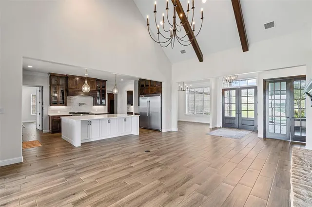 a large kitchen with stainless steel appliances kitchen island granite countertop a sink a counter space and a view of living room