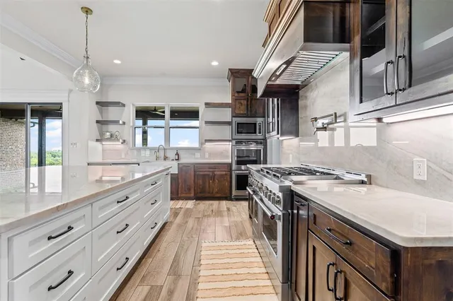 a large kitchen with granite countertop a stove top oven a sink a counter space and stainless steel appliances