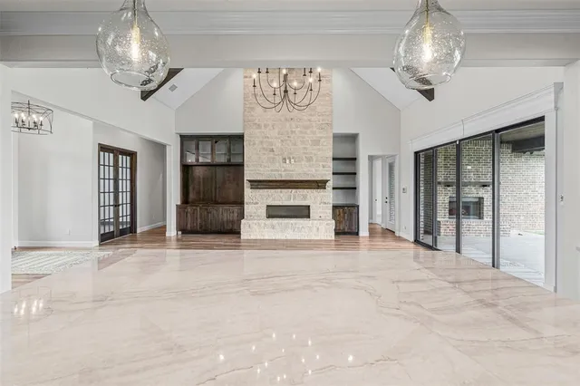 a view of a livingroom with a fireplace a chandelier and windows