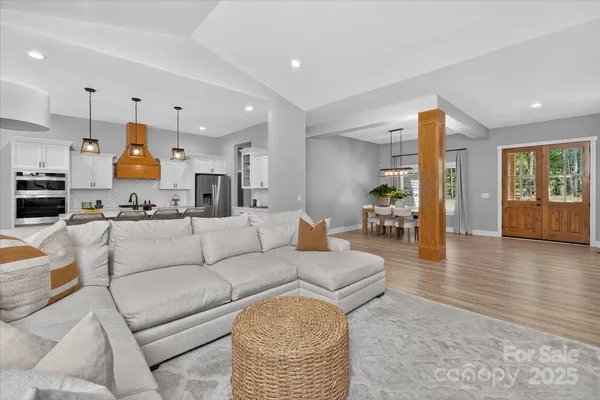 a living room with furniture kitchen view and a wooden floor
