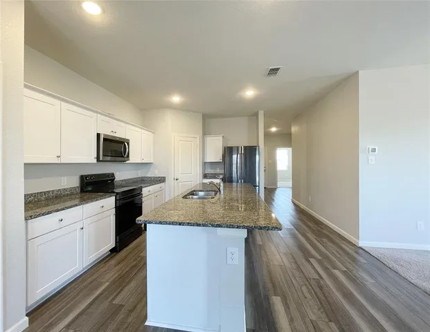 a kitchen with granite countertop a sink cabinets and stainless steel appliances