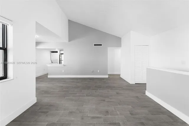 a view of empty room with wooden floor and windows