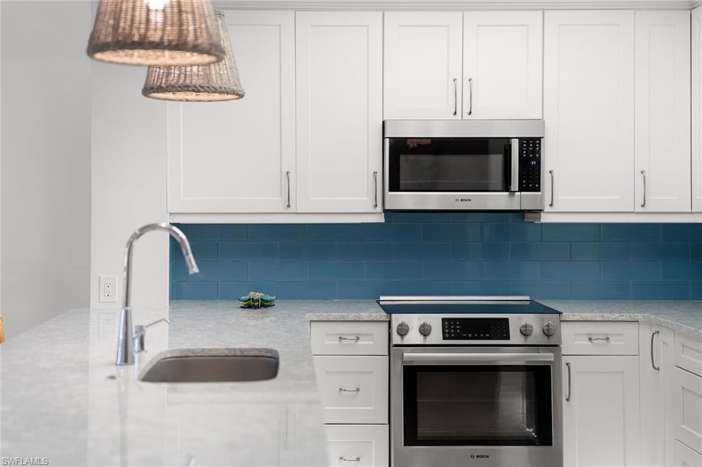 411 6th Street South, Unit 202 Naples, FL 34102 - Photo 10 of 35 a kitchen with granite countertop white cabinets stainless steel appliances and a sink
