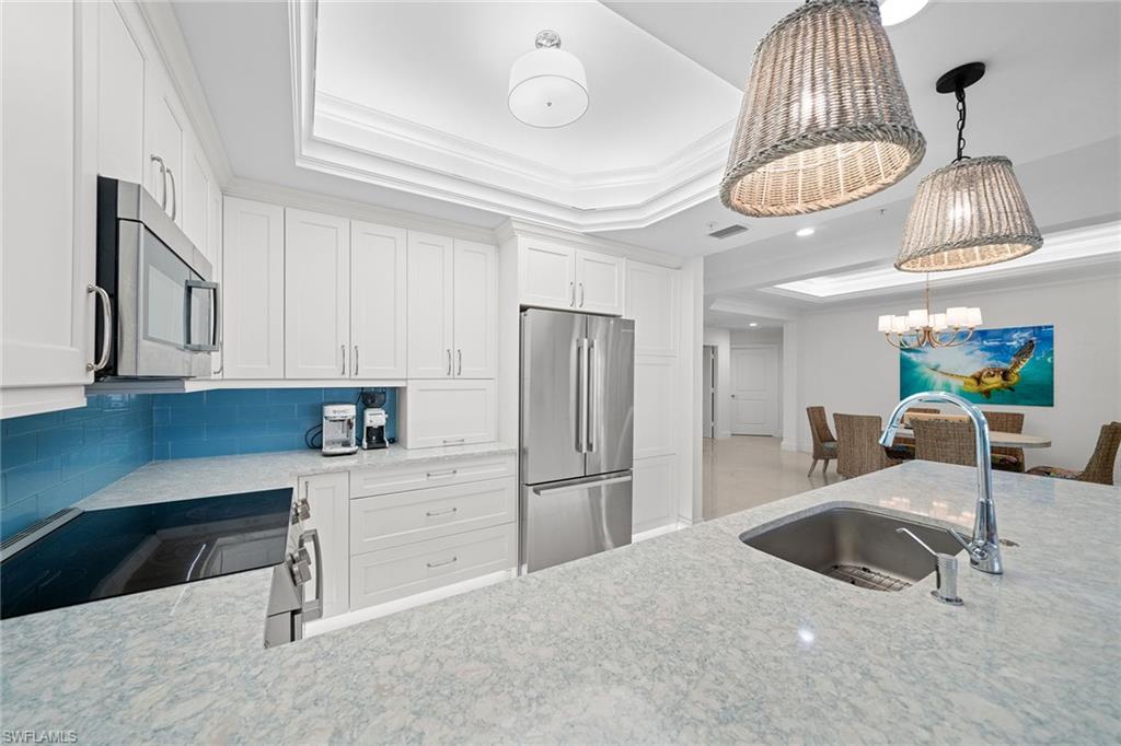 411 6th Street South, Unit 202 Naples, FL 34102 - Photo 12 of 35 a kitchen with stainless steel appliances a table chairs and a refrigerator