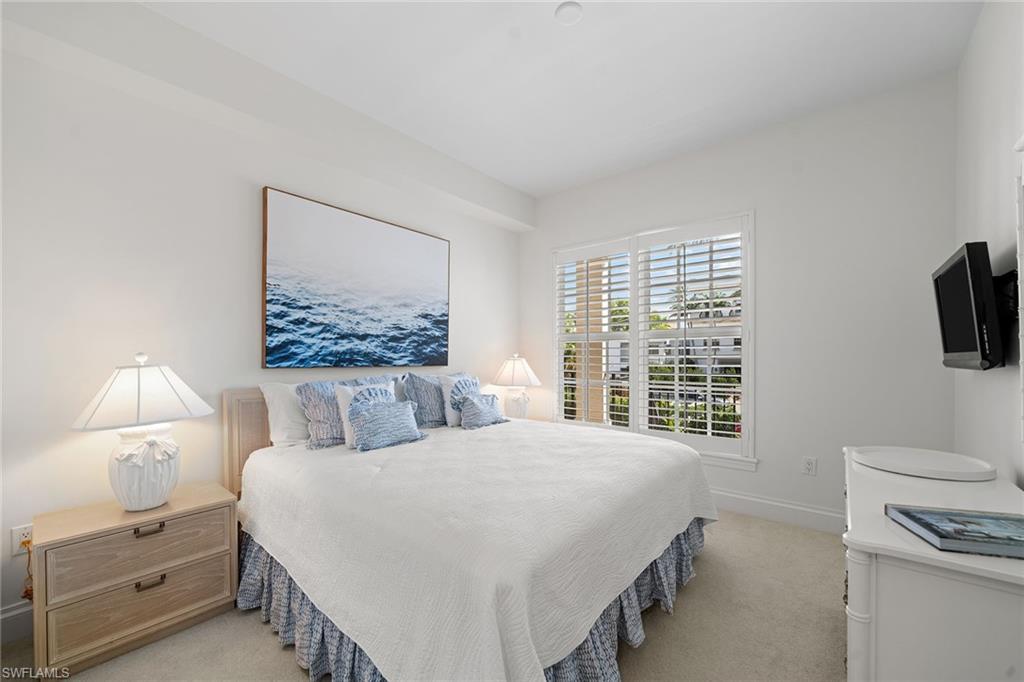 411 6th Street South, Unit 202 Naples, FL 34102 - Photo 16 of 35 a bedroom with a bed and a lamp on dresser next to a window