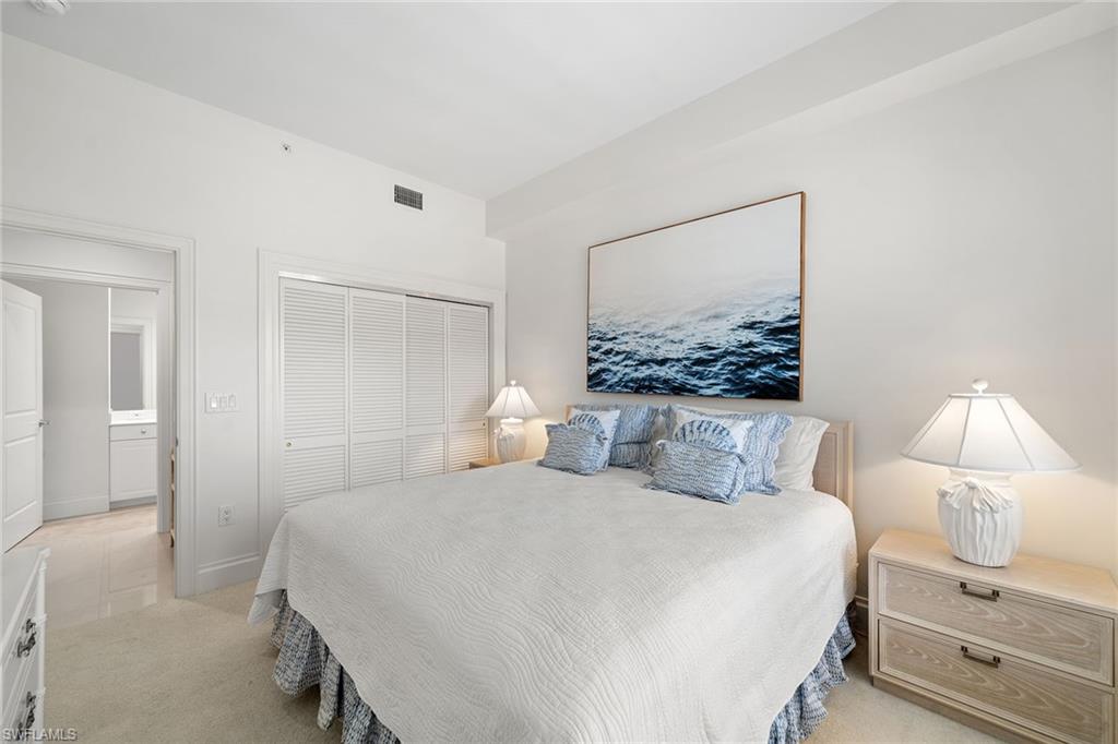 411 6th Street South, Unit 202 Naples, FL 34102 - Photo 17 of 35 a bedroom with a large bed and a lamp