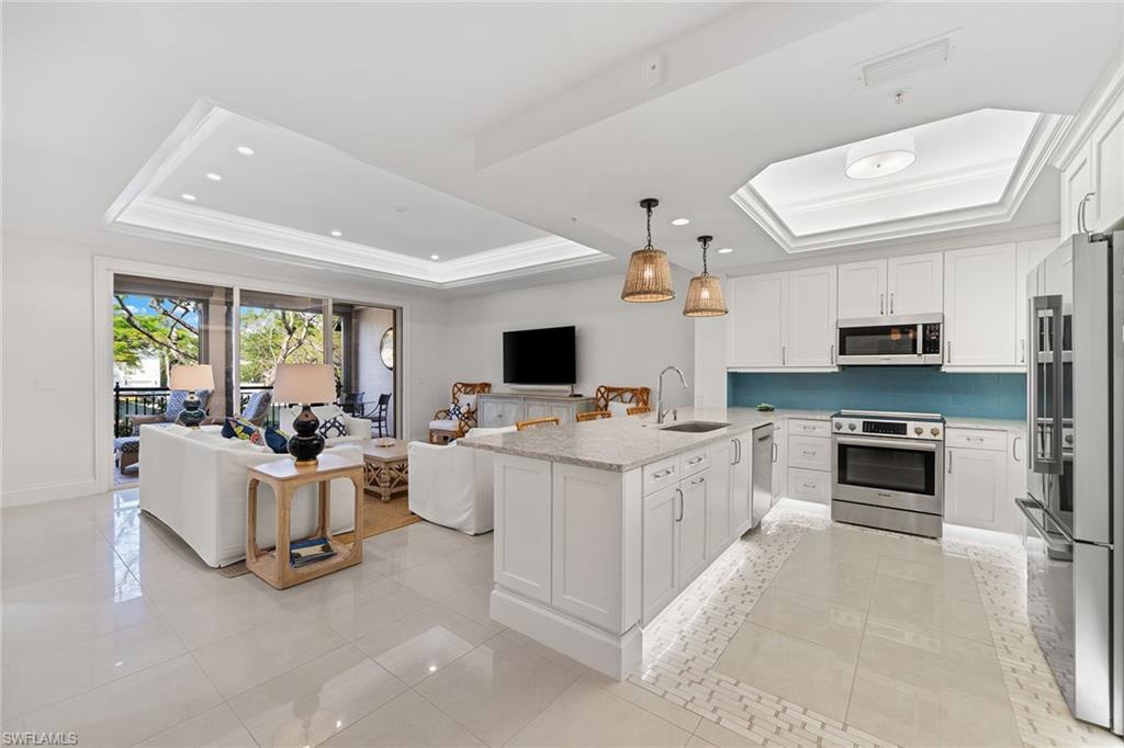 411 6th Street South, Unit 202 Naples, FL 34102 - Photo 35 of 35 a white kitchen with stainless steel appliances kitchen island granite countertop a stove and a sink