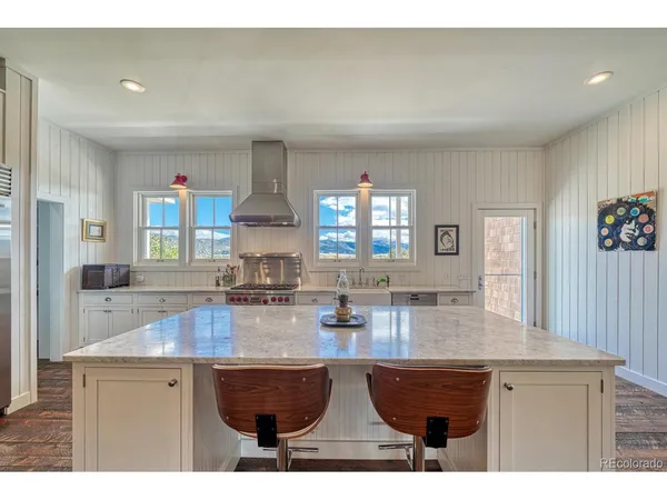 a large kitchen with stainless steel appliances granite countertop a large counter top a stove and a wooden floors
