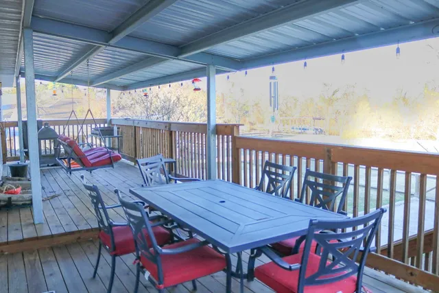 a patio with wooden floor a yard a table and chairs