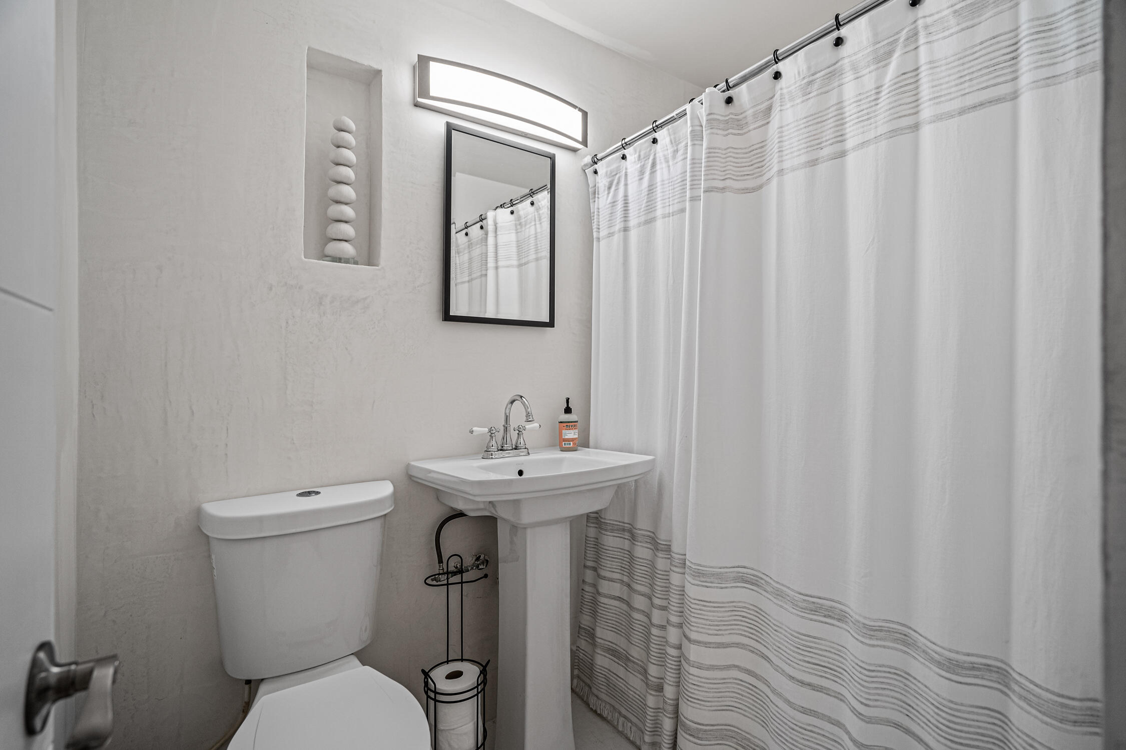 2330 North Ocean Boulevard Boca Raton, FL 33431 - Photo 31 of 31 a bathroom with a sink a toilet a mirror and shower curtain