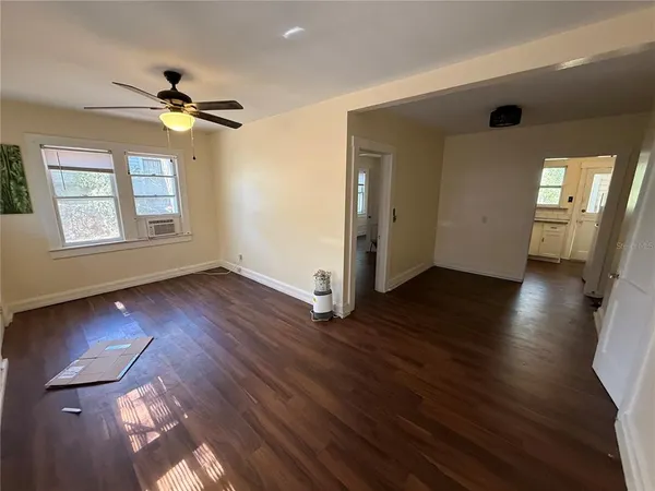 a view of an empty room with a window and wooden floor