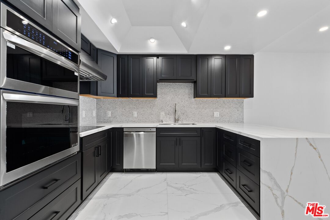 1100 Alta Loma Road, Unit 902 West Hollywood, CA 90069 - Photo 4 of 17 a kitchen with stainless steel appliances kitchen island granite countertop a sink and cabinets