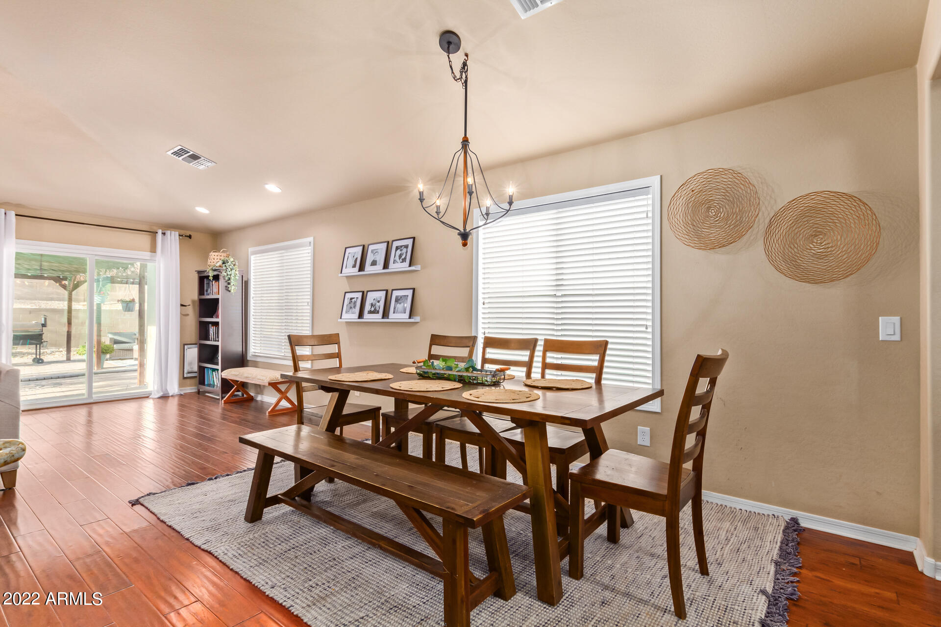 20748 West White Rock Road Buckeye, AZ 85396 - Photo 9 of 34 a dining room with wooden floor a chandelier a wooden table and chairs