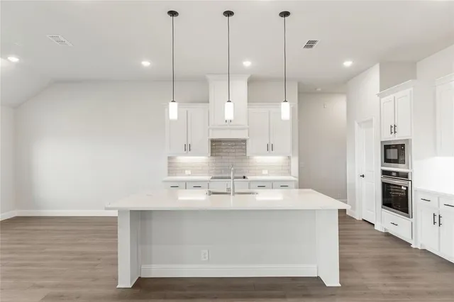 a large kitchen with kitchen island a counter space stainless steel appliances and cabinets