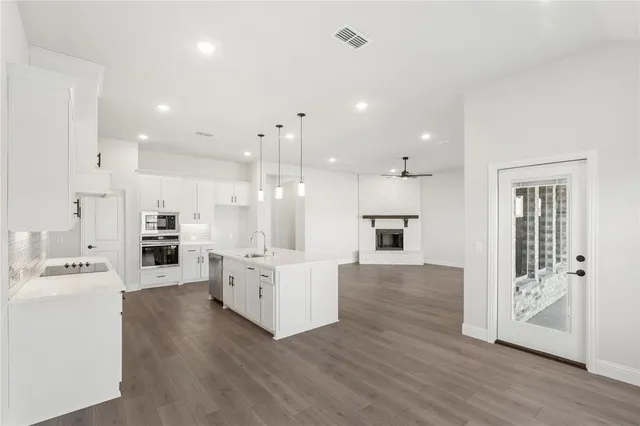 a large white kitchen with lots of counter space wooden floor and appliances