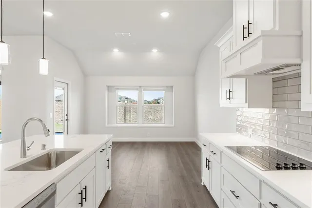 a view of a kitchen with kitchen island a sink wooden floor and a living room view