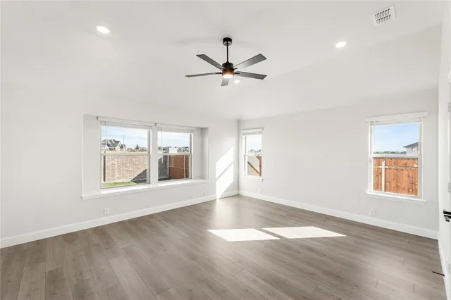 a view of empty room with wooden floor and fan