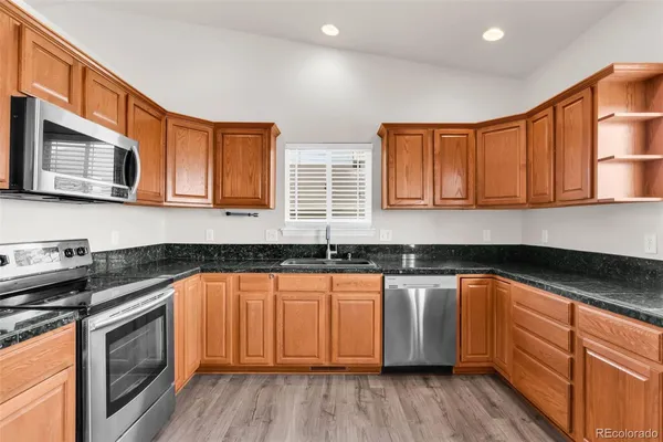 a kitchen with stainless steel appliances granite countertop wooden cabinets and a stove top oven