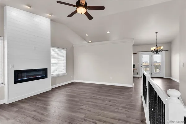 an empty room with wooden floor a ceiling fan and windows