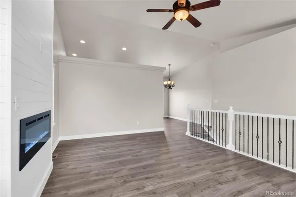 a view of a livingroom with a fireplace wooden floor and chandelier fan