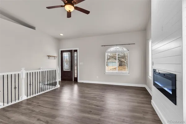 an empty room with wooden floor fan and windows