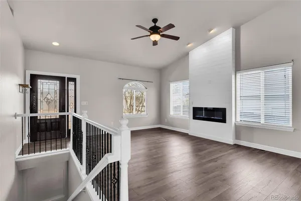 an empty room with wooden floor a ceiling fan and windows