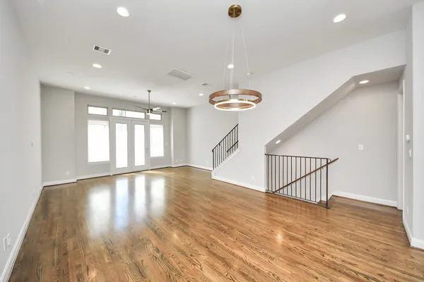 a view of a room with wooden floor ceiling fan and kitchen view