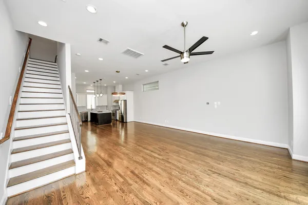 a view of a living room with wooden floor and kitchen view