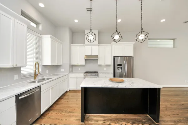 a kitchen with a refrigerator a sink and dishwasher with wooden floor