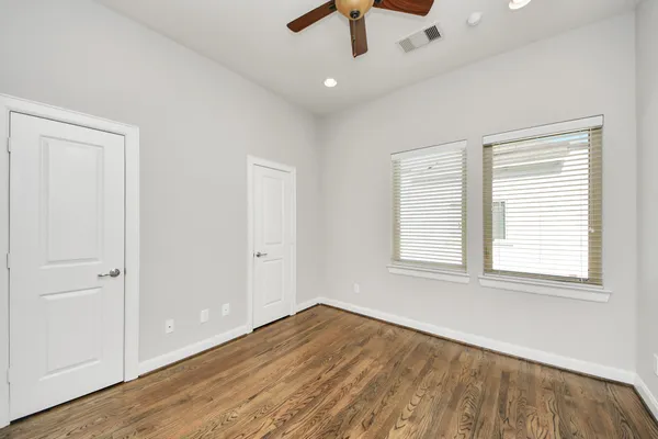 an empty room with wooden floor and ceiling fan