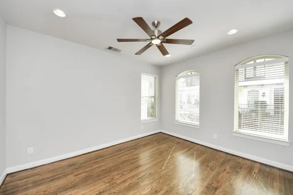 an empty room with wooden floor and windows