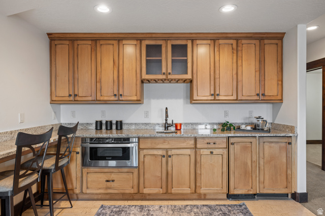 707 Chimney Rock Road, Unit 247 Heber City, UT 84032 - Photo 21 of 64 Kitchen with brown cabinetry, light stone counters, recessed lighting, glass insert cabinets, and stainless steel microwave