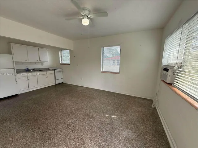 a large white kitchen with granite countertop a stove a sink a window and a refrigerator