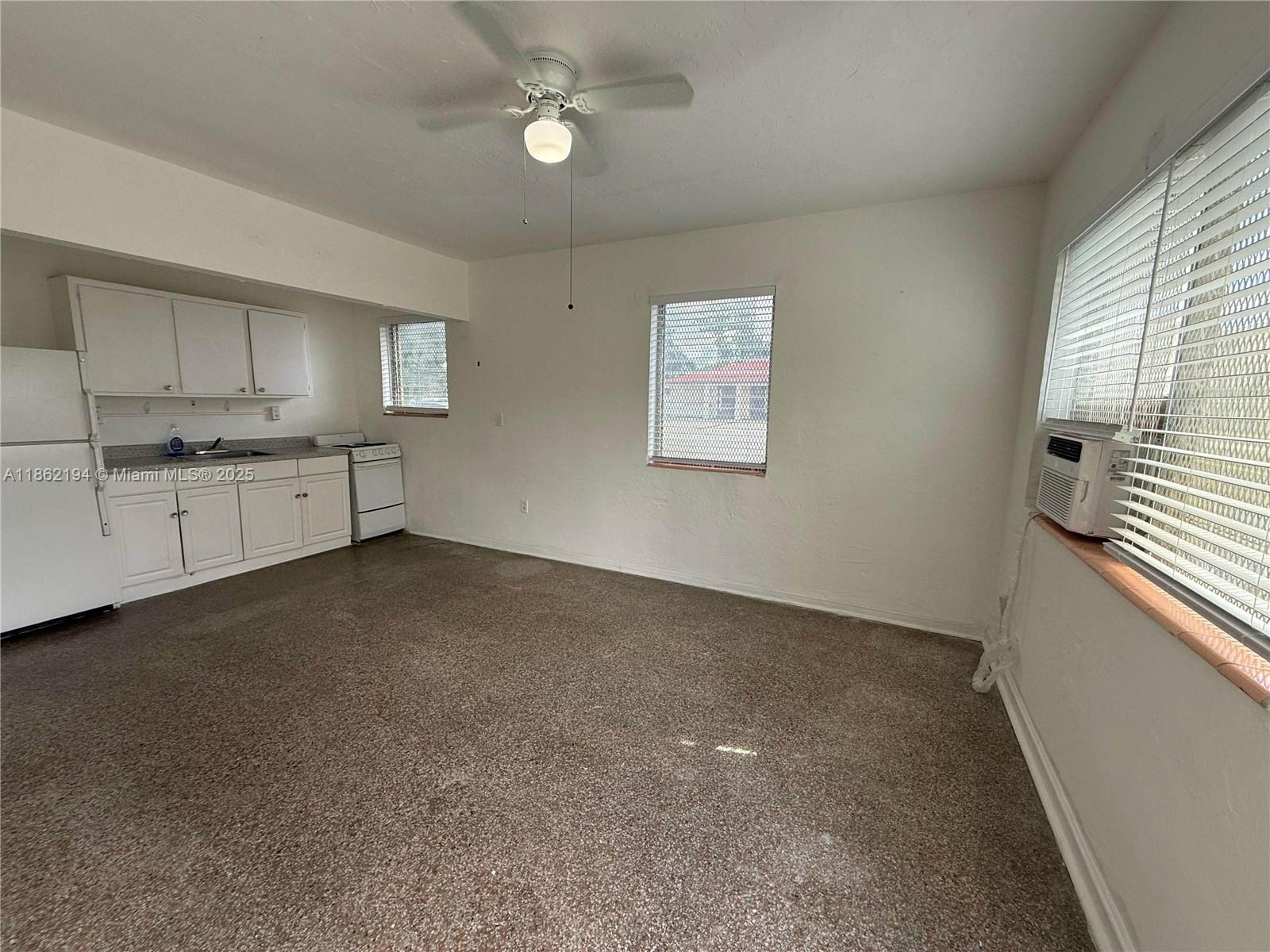 361 Sharar Avenue, Unit 1 Opa-Locka, FL 33054 - Photo 3 of 11 a large white kitchen with granite countertop a stove a sink a window and a refrigerator