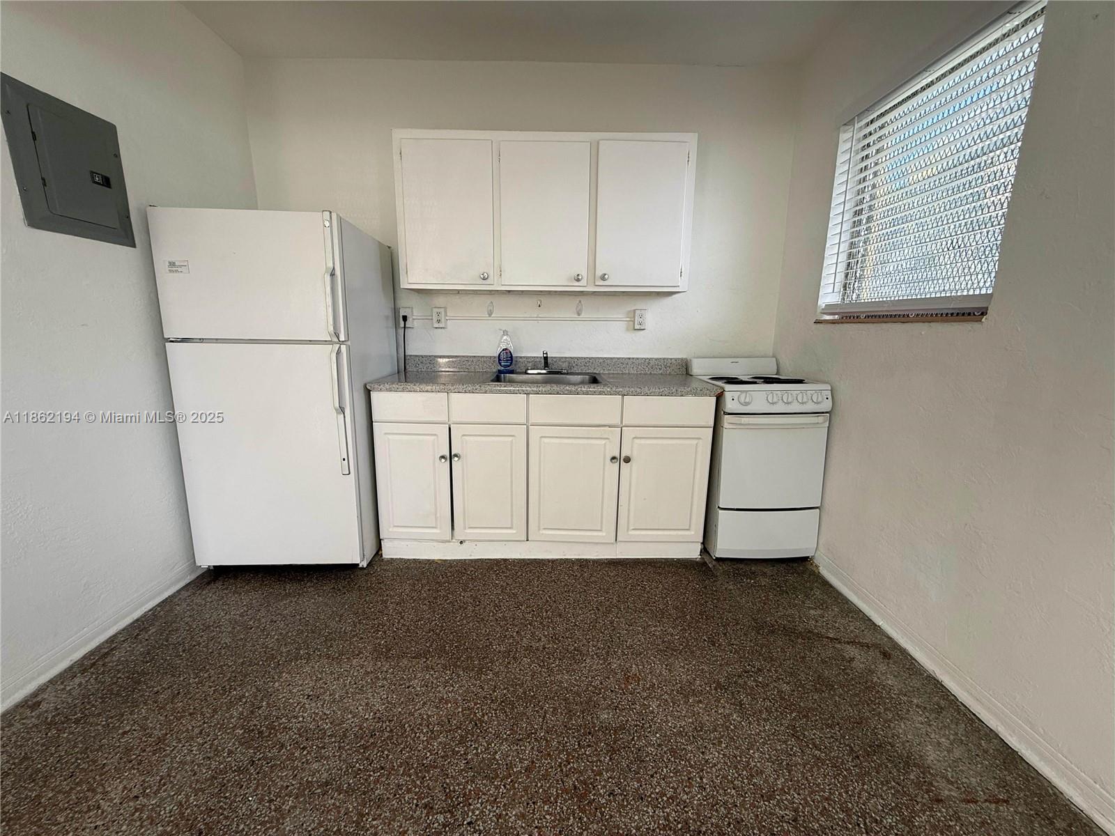361 Sharar Avenue, Unit 1 Opa-Locka, FL 33054 - Photo 4 of 11 a kitchen with cabinets and white appliances