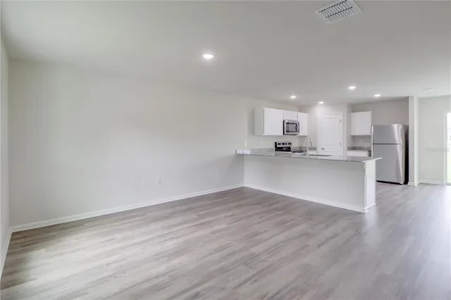 a view of kitchen with kitchen island wooden floor center island and stainless steel appliances