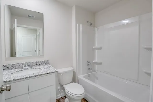 a bathroom with a granite countertop sink a toilet and shower