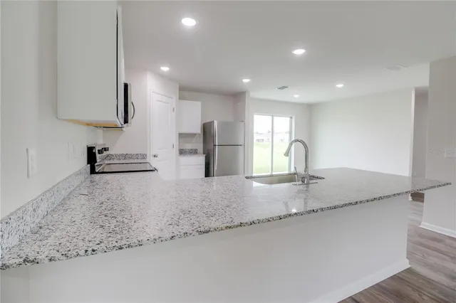 a large kitchen with granite countertop a sink and a stove top oven with wooden floor