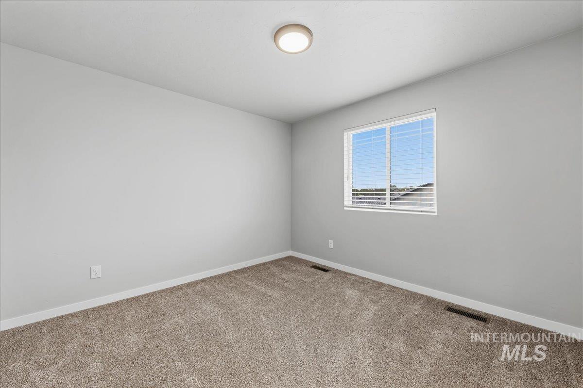 12475 West Victory Road Boise, ID 83709 - Photo 17 of 26 Carpeted room with light gray walls, a flush-mount ceiling light, and a window with horizontal blinds