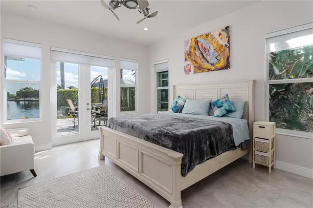 a spacious bedroom with a bed painting on wall and a large window