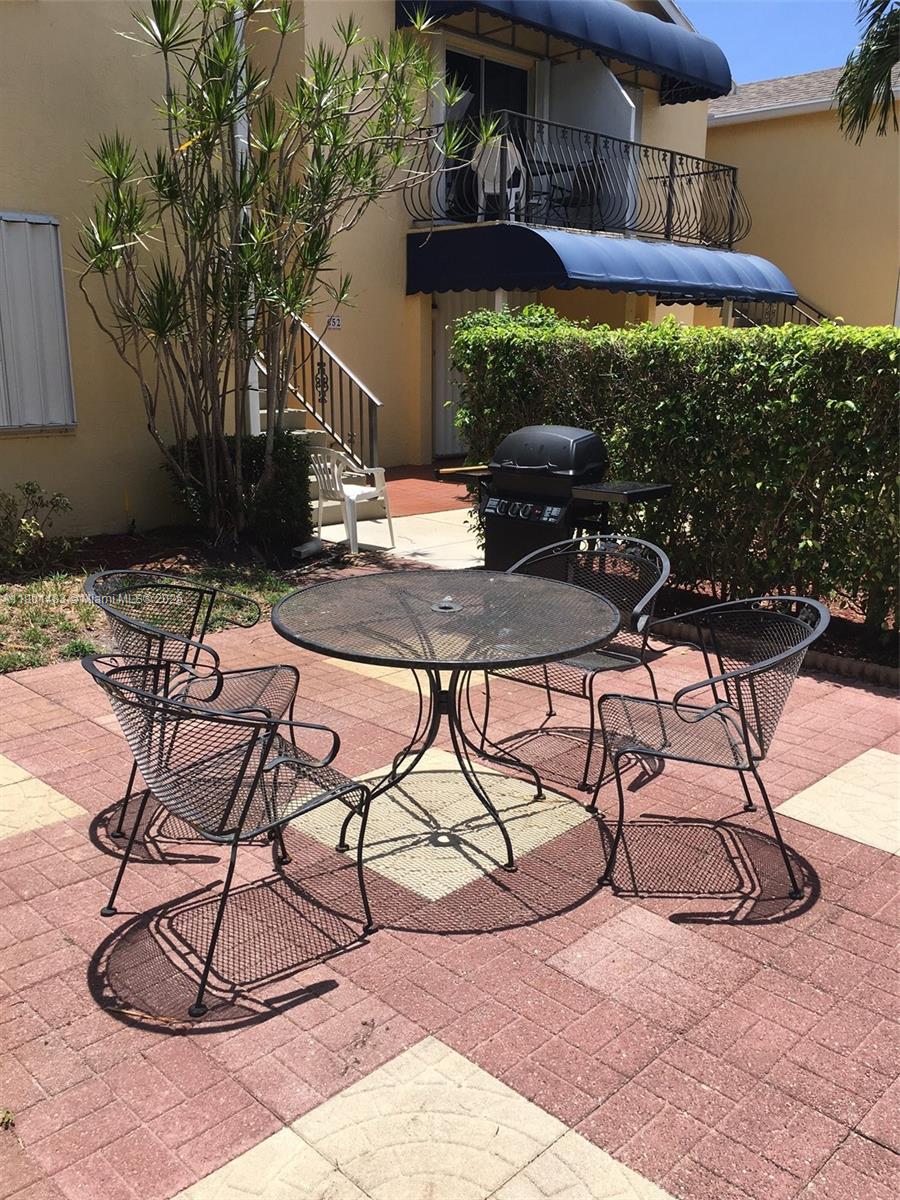 653 Waterside Drive, Unit 653 Hypoluxo, FL 33462 - Photo 2 of 12 a patio with a table and chairs under an umbrella