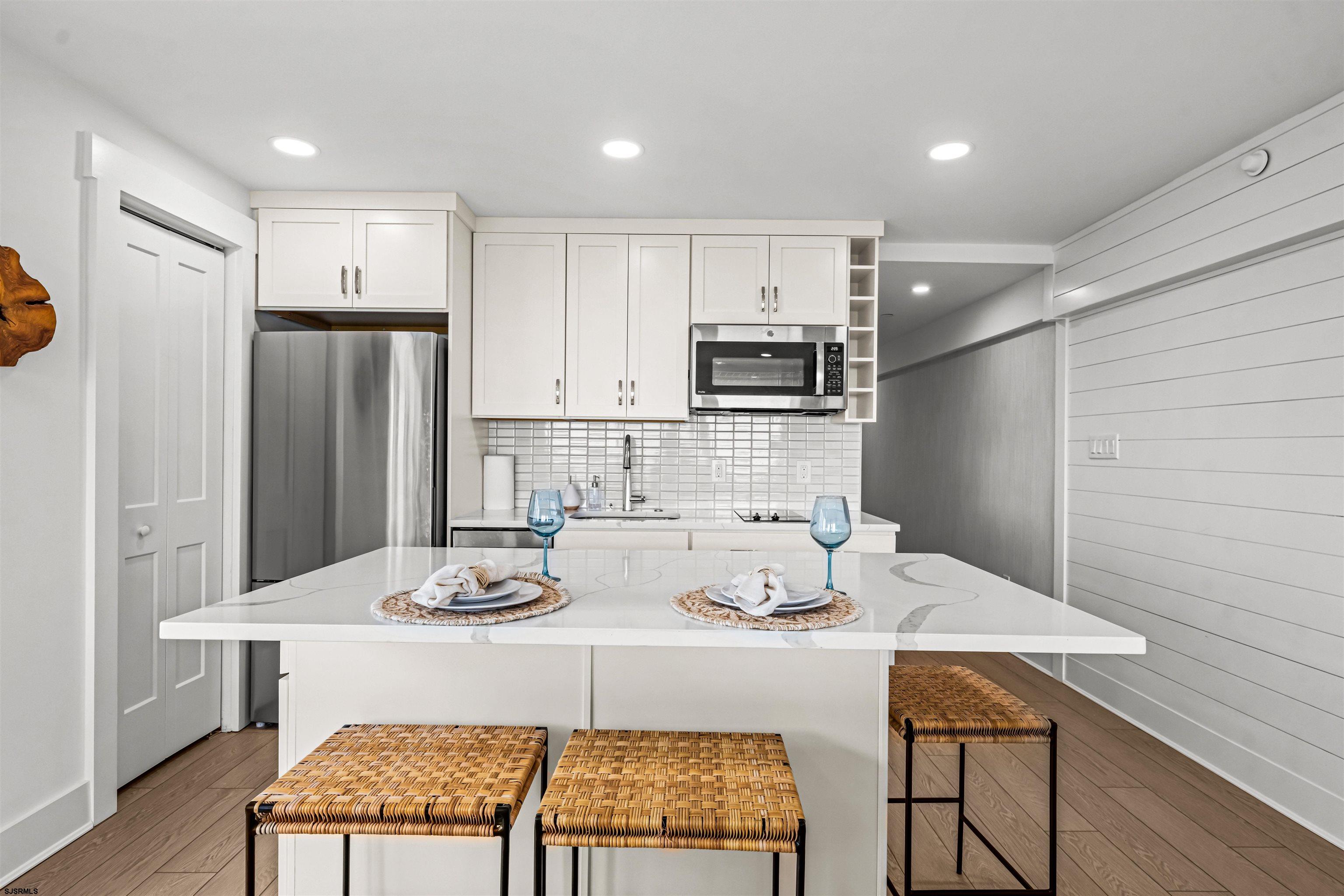 321 6th Street South, Unit 14 Brigantine, NJ 08203 - Photo 11 of 21 a kitchen with stainless steel appliances kitchen island granite countertop a dining table chairs and refrigerator