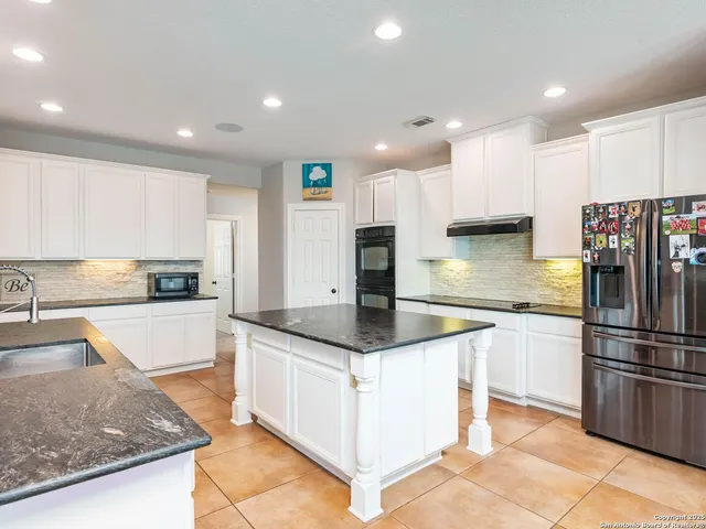 a kitchen with stainless steel appliances granite countertop a sink and a refrigerator