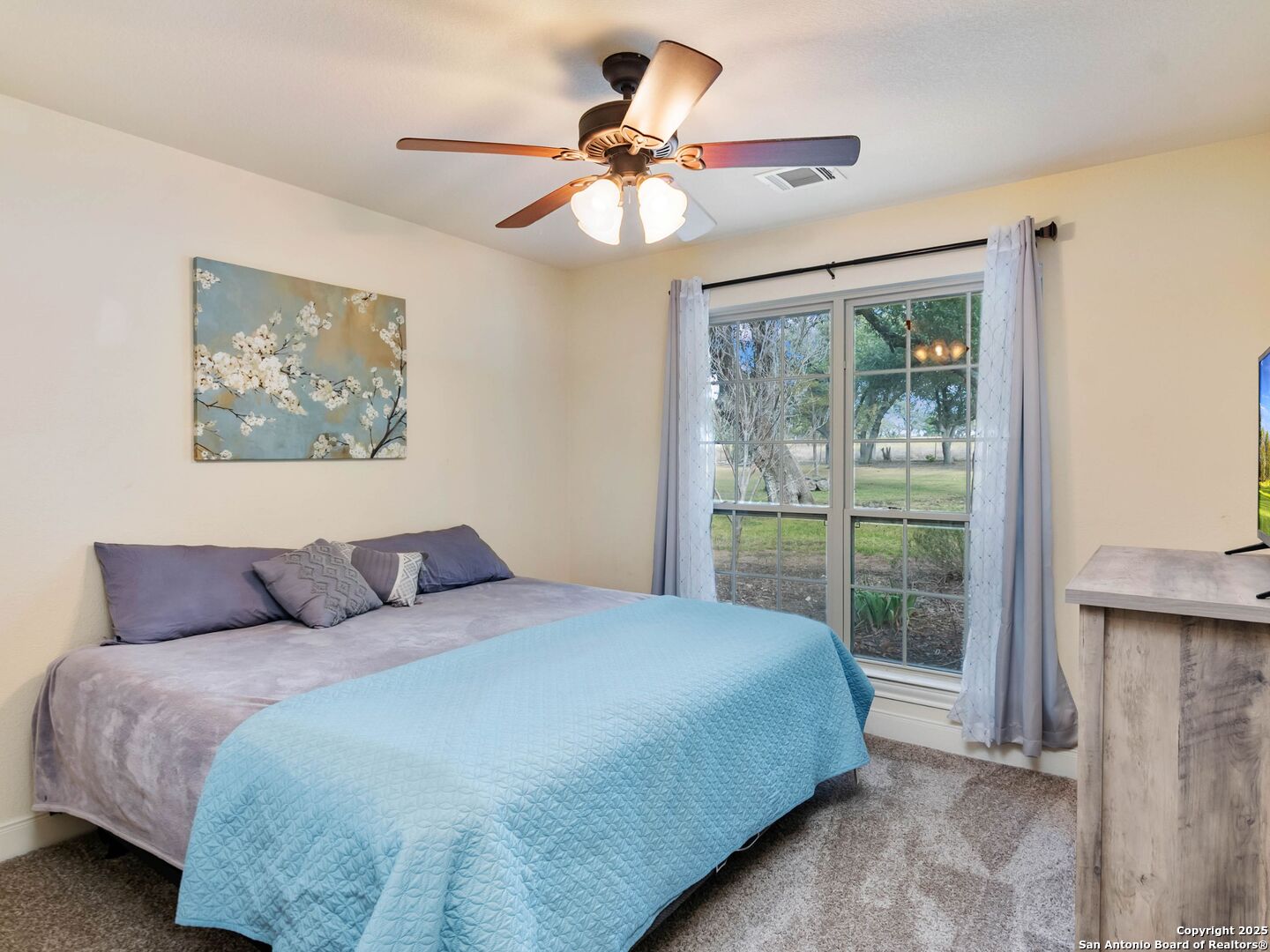 272 Schaper Road Fredericksburg, TX 78624 - Photo 27 of 62 a bedroom with a large bed and a chandelier